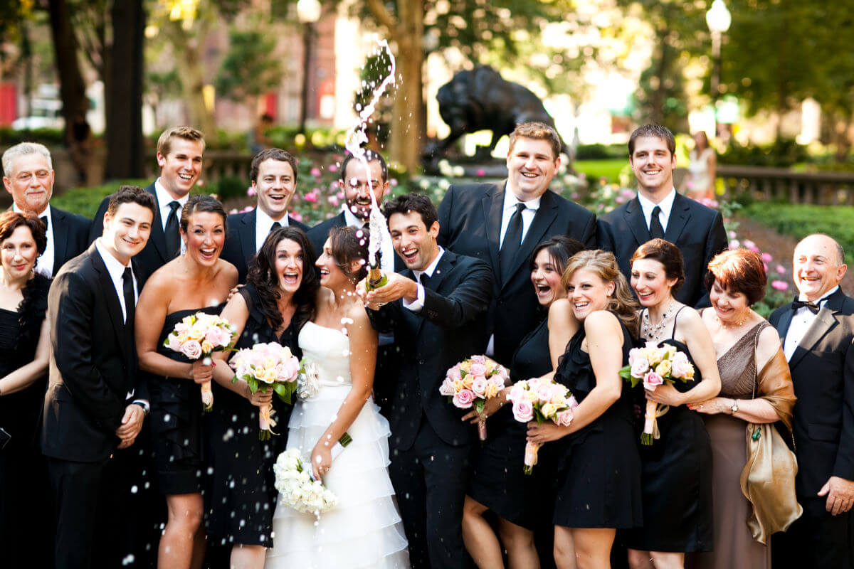 Laughing Bride And Groom Pose For A Fun Portrait With Their Friends
