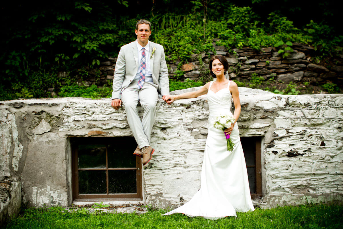 Wedding Couple Posing On The Wall Surrounded By Untouched Nature